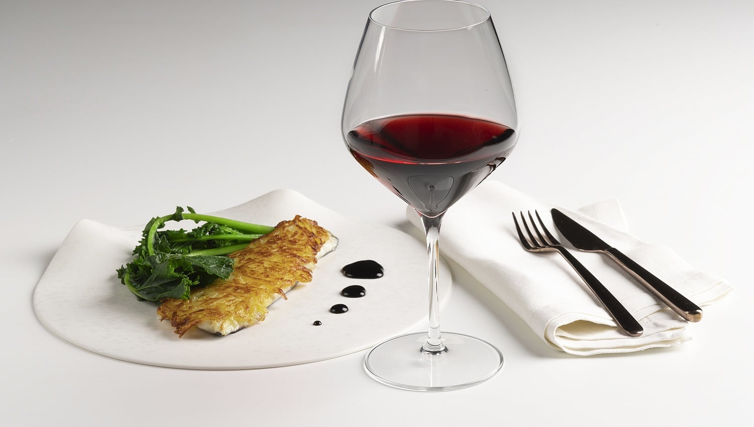 Seebarschfilet mit Kartoffelkruste, Rotweinreduktion und Stängelkohl