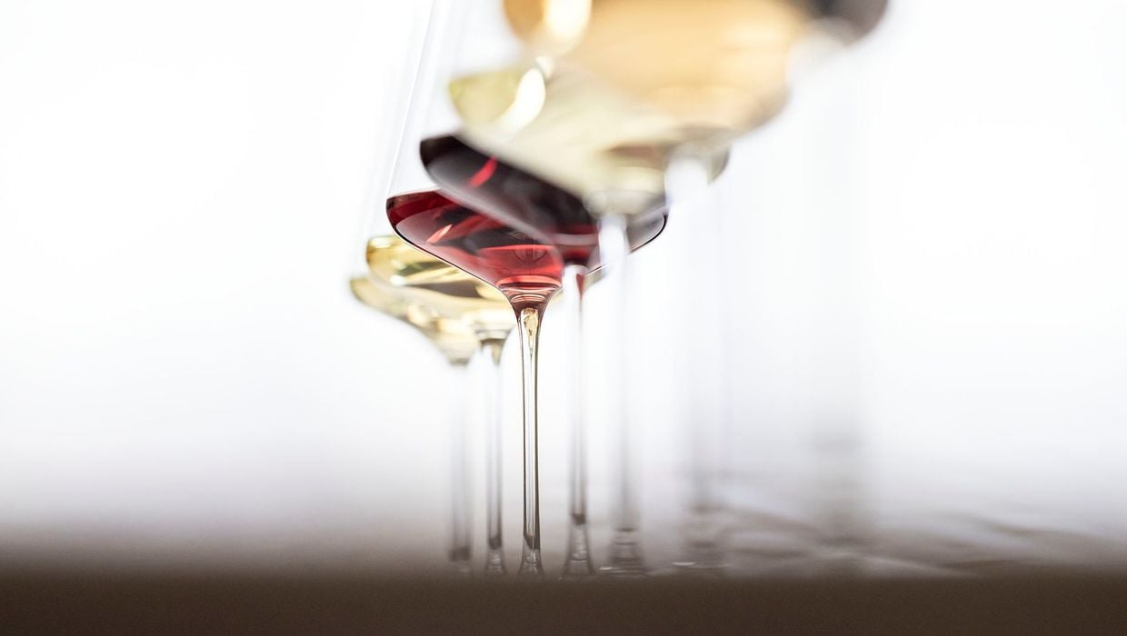 Eine Reihe von verschiedenen Weingläsern, welche Rotweine und Weißweine enthalten.