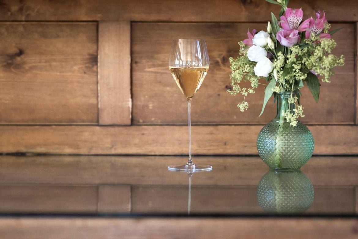 Ein einzelstehendes gefülltes Sektglas neben einem Blumenstraus.